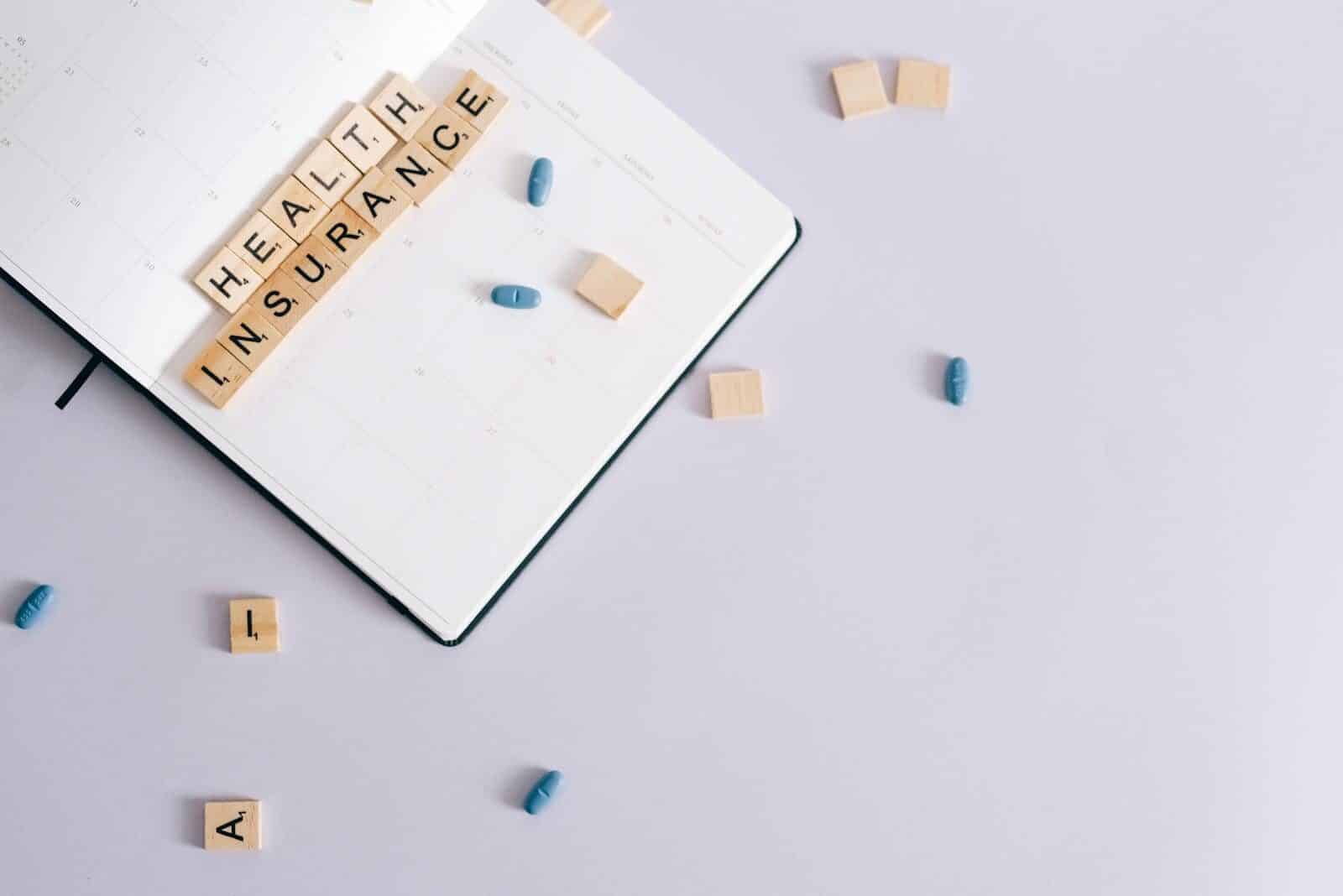 Flat lay of health insurance concept with planner and pills.