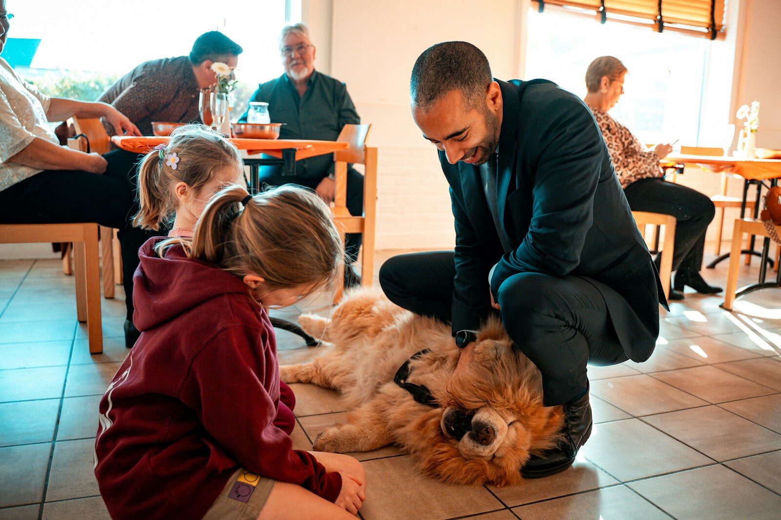 Man pets a fluffy dog with a child watching