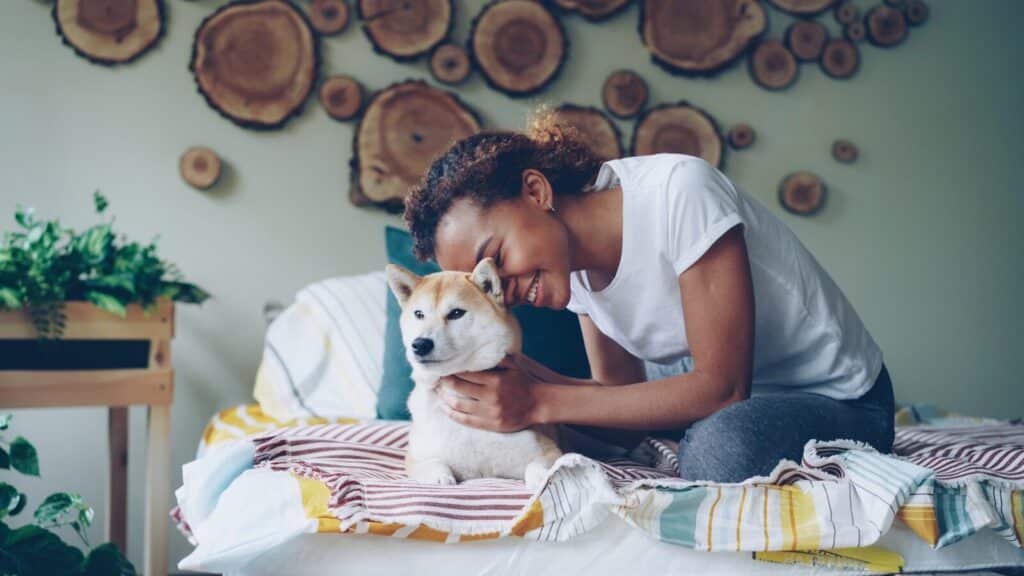Woman cuddles her dog on a bed.